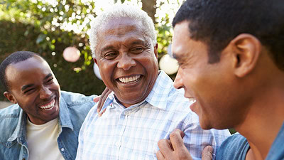 Three men are shown laughing in a garden in this stock image.