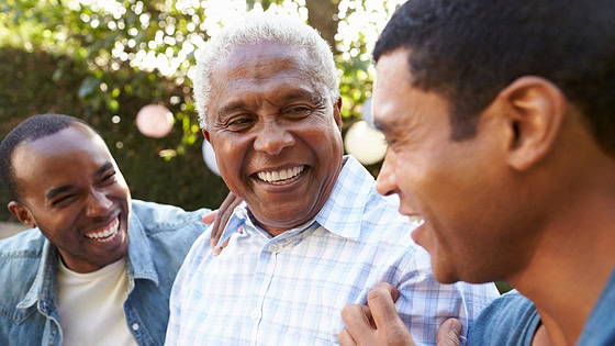 Three men are shown laughing in a garden in this stock image.