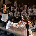 A student dons her white coat during the College of Nursing ceremony.