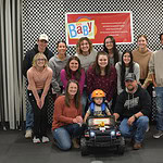 Students and faculty present a GoBabyGo modified ride-on care to a child with mobility issues.