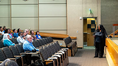 Harriet Washington stands in front of the stage in Smith Auditorium while discussing the history in the U.S, of racial health disparities.