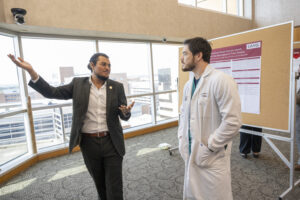 photo of a doctor and another man discussing a poster. Poster presentations outside the auditorium attracted a lot of discussion.