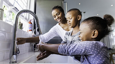 Mother and two children at kitchen sink washing hands