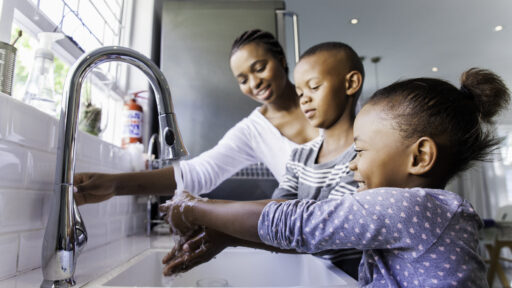 Mother and two children at kitchen sink washing hands