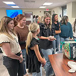 High school students look at a NICU maniken.