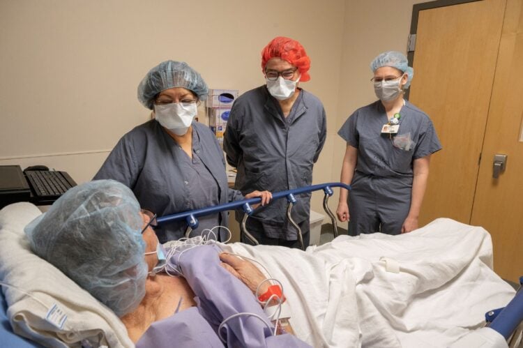 L-R) Ranu Jung, Ph.D., James Abbas, Ph.D., and Erika Petersen, M.D., chat with Dewey Hickey prior to his historic surgery.