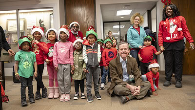 UAMS Chancellor Cam Patterson, M.D., MBA, poses with the carolers and their leaders for a photo.