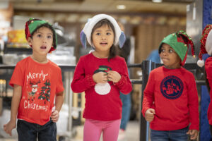 A close-up of three carolers singing