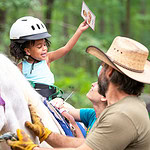 Therapists, volunteers and graduate students interact with a child in the UAMS hippotherapy program.