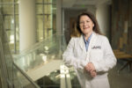 Ashley Booth Norris, M.D., standing in white coat inside UAMS.