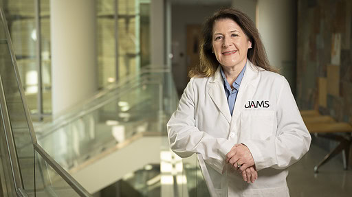 Ashley Booth Norris, M.D., standing in white coat inside UAMS.