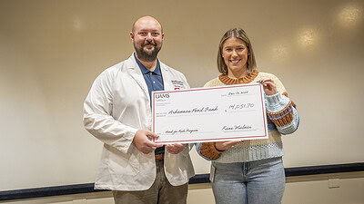 Kane Malnar, left, presents Claire Tiffin with a ceremonial check, representing the funds raised by PA students.