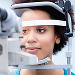 Optician measuring women eyes with refractometer