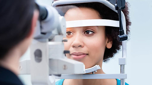 Optician measuring women eyes with refractometer