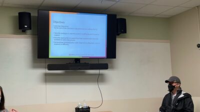 Matthew Boone, LCSW, sits in front of a group of faculty members near a screen that reiterates points about helping students in difficulty.