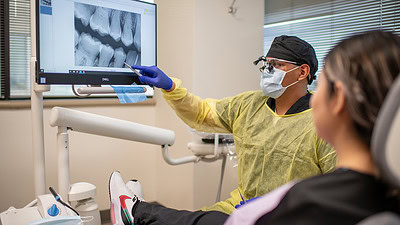 A patient in the UAMS Dental Hygiene Clinic listens to an analysis of an x-ray of her teeth.