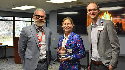 Jennifer Vincenzo, center, receives her Chancellor's Excellence Award from Ryan Cork, left, and Eric Leemis, right.