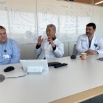 Photo of three people seated at long table with calculations on a white board in back of them: from left to right, Yuri Chepurnyi, M.D., James Suen, M.D., and Mauricio Moreno, M.D.