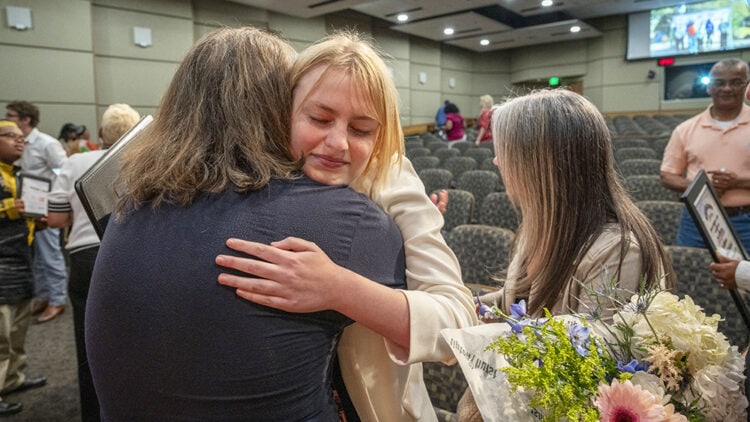 Project SEARCH graduate Sunny Welch, center, and a well-wisher share a hug after the graduation ceremony.