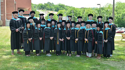 The UAMS Physical Therapy Class of 2025 poses in their caps and gowns on the lawn of the UAMS Northwest Regional Campus in Fayetteville.