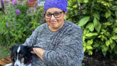 Image of the patient, Edis Sierra, sitting outside her house with her dog, Shammy.