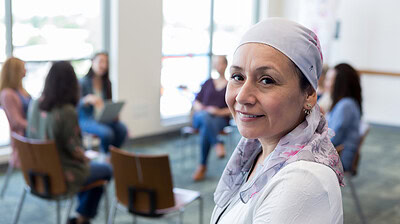 Portrait of cancer survivor with support group in background