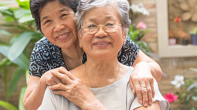 This portrait shows two older women smiling in a garden.