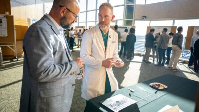 Gresham Richter, M.D. (right), discusses his BioVentures-supported invention, the Smart Tracheal Collar, with Dan Voth, Ph.D.
