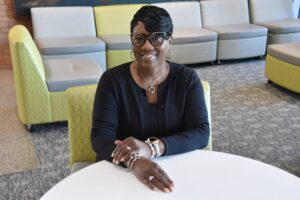Treneica McKnight, department finance administrator in the UAMS College of Nursing, is sitting at a table in the UAMS Daniel W. Rahn Interprofessional Education Building.
