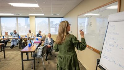 An instructor at a DEEP Training Workshop takes notes on a whiteboard.