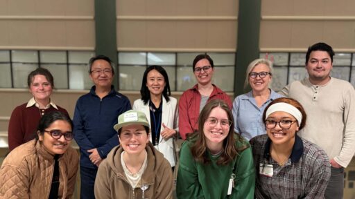 group photo: Yunmeng Liu, Ph.D., in white coat, with members of her laboratory.
