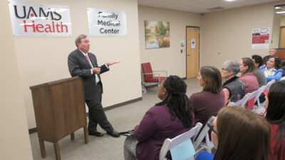 C. Lowry Barnes, UAMS chancellor, gestures at podium as he talks to room of employees
