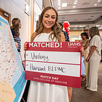 Haya Safar stands beside a map showing where all the UAMS seniors are going, holding a sign announcing that she matched at Beth Israel Deaconess Medical Center at Harvard in Boston.