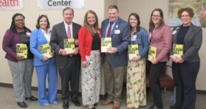 Lineup of employees with Dr. Barnes, holding hospitality books