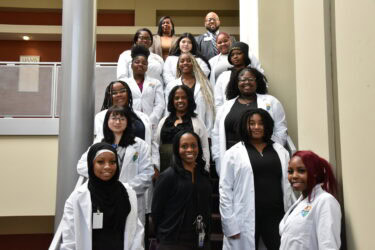 Students and instructors from the Hall-West High School of Innovation are shown at UAMS. In the back row are Nicholas Pettus, manager of student recruitment for UAMS Academic Pathways and Workforce Partnerships, and Bridgette Edmondson, a program facilitator.