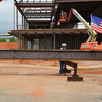 A metal i-beam, signed by attendees at the topping out ceremony for the UAMS Health Orthopaedics & Sports Medicine Hospital in Springdale, is ready to be hoisted in place by a crane.