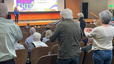 Image from a previous Parkinson's symposium showing the audience from the back (top) of the auditorium, some participating in Parkinson's exercises.