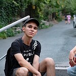 Two teens sitting on a rural road and looking at the camera