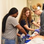 Andersyn Van Kuren, a 10th grader at Parkview Arts and Science Magnet High School in Little Rock, performs chest compressions on a manikin during a trauma-care simulation in the UAMS Simulation Center.
