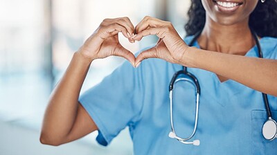 Smiling nursing making a heart gesture with her hands.