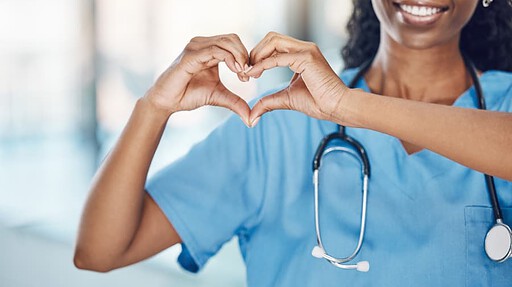 Smiling nursing making a heart gesture with her hands.