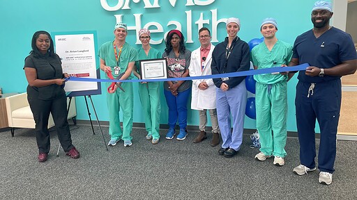 photo of Dr. Brian Langford preparing to cut ribbon, in a line with seven other people.