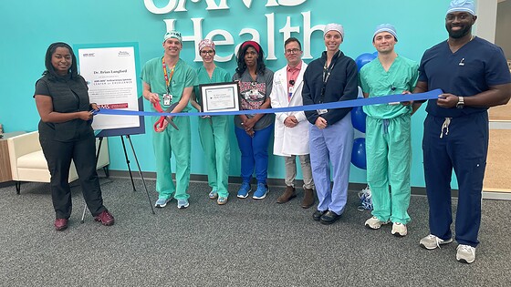 photo of Dr. Brian Langford preparing to cut ribbon, in a line with seven other people.