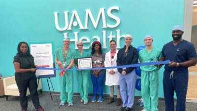 photo of Dr. Brian Langford preparing to cut ribbon, in a line with seven other people.