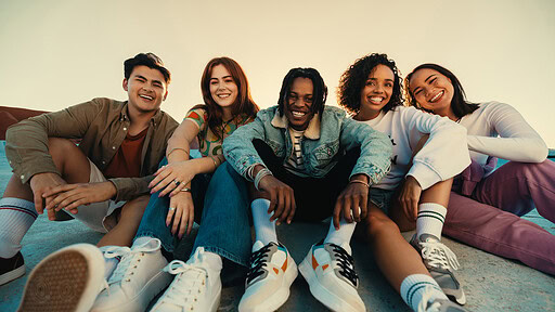 Gen Z friends sitting together outdoors, posing and smiling