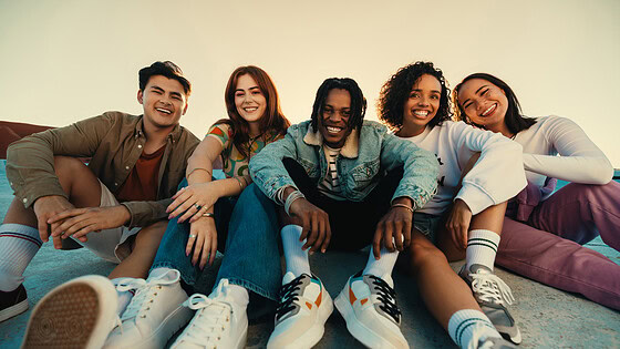 Gen Z friends sitting together outdoors, posing and smiling