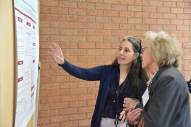 Dominique DuBois (left), instructor in the UAMS College of Nursing and assistant director of the Nurse-Midwifery Program, discusses one of the posters set up outside the auditorium at Arkansas Nursing Research Day.