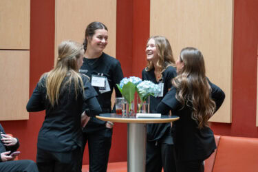 Four women share a laugh as they stand around a table during a break between sessions at Arkansas Nursing Research Day.