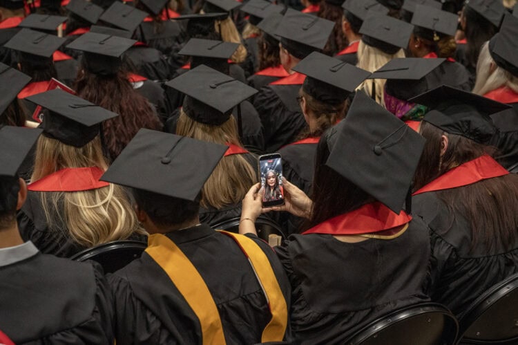 One of the graduating students takes a selfie while waiting for the start of the ceremony.