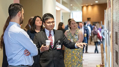 Residents discuss a research poster at the conference